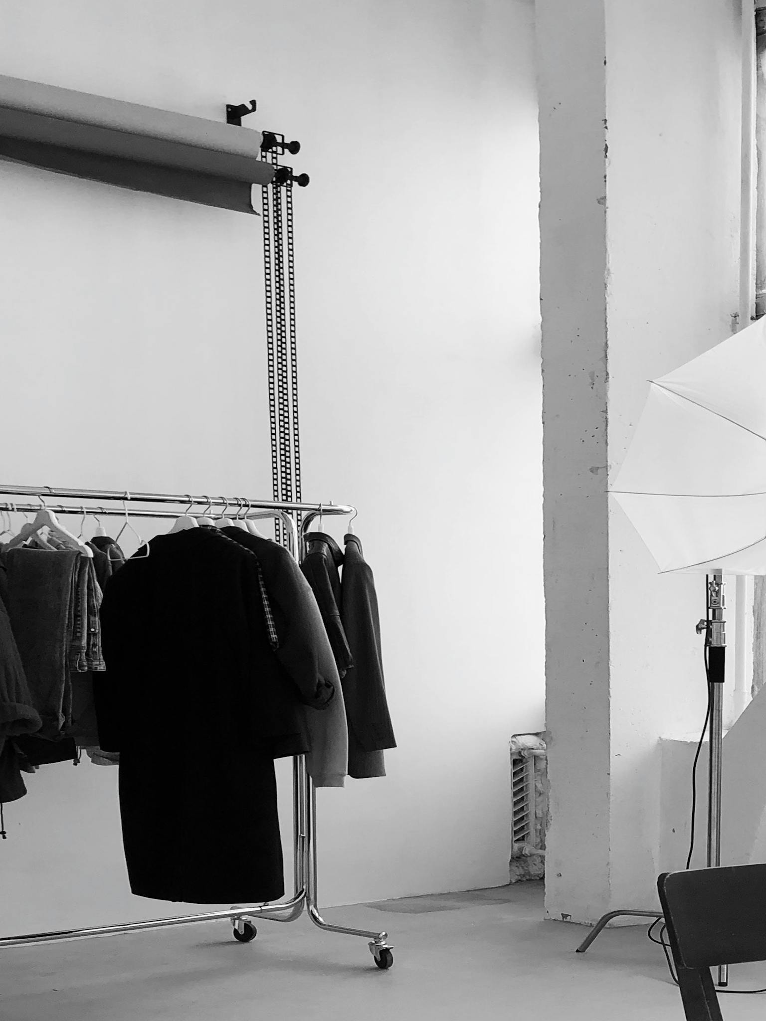 A contemporary studio setup featuring clothing racks and professional photography lighting.